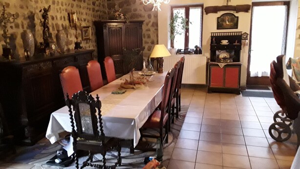 A dining room with a long table, chairs, a chandelier, and a fireplace. - GRANGE-GITE by ROCHEBARON (bas en basset)