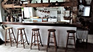A kitchen with a bar area, stools, and hanging pots. - GRANGE-GITE by ROCHEBARON (bas en basset)