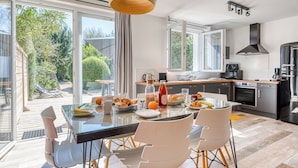 A modern kitchen with a dining area, large windows, and a view of the outdoors.