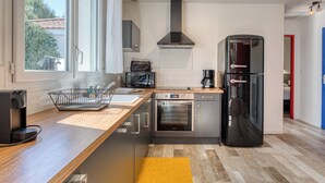 A modern kitchen with a large window, a built-in oven, a coffee maker, and a refrigerator.
