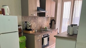 Una cocina compacta con refrigerador, estufa, lavaplatos y un comedor con mesa y sillas.
