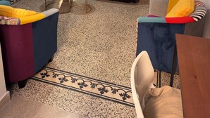 Una sala de estar con un sofá, dos sillones, una mesita redonda, un aparador y un ventilador de techo.