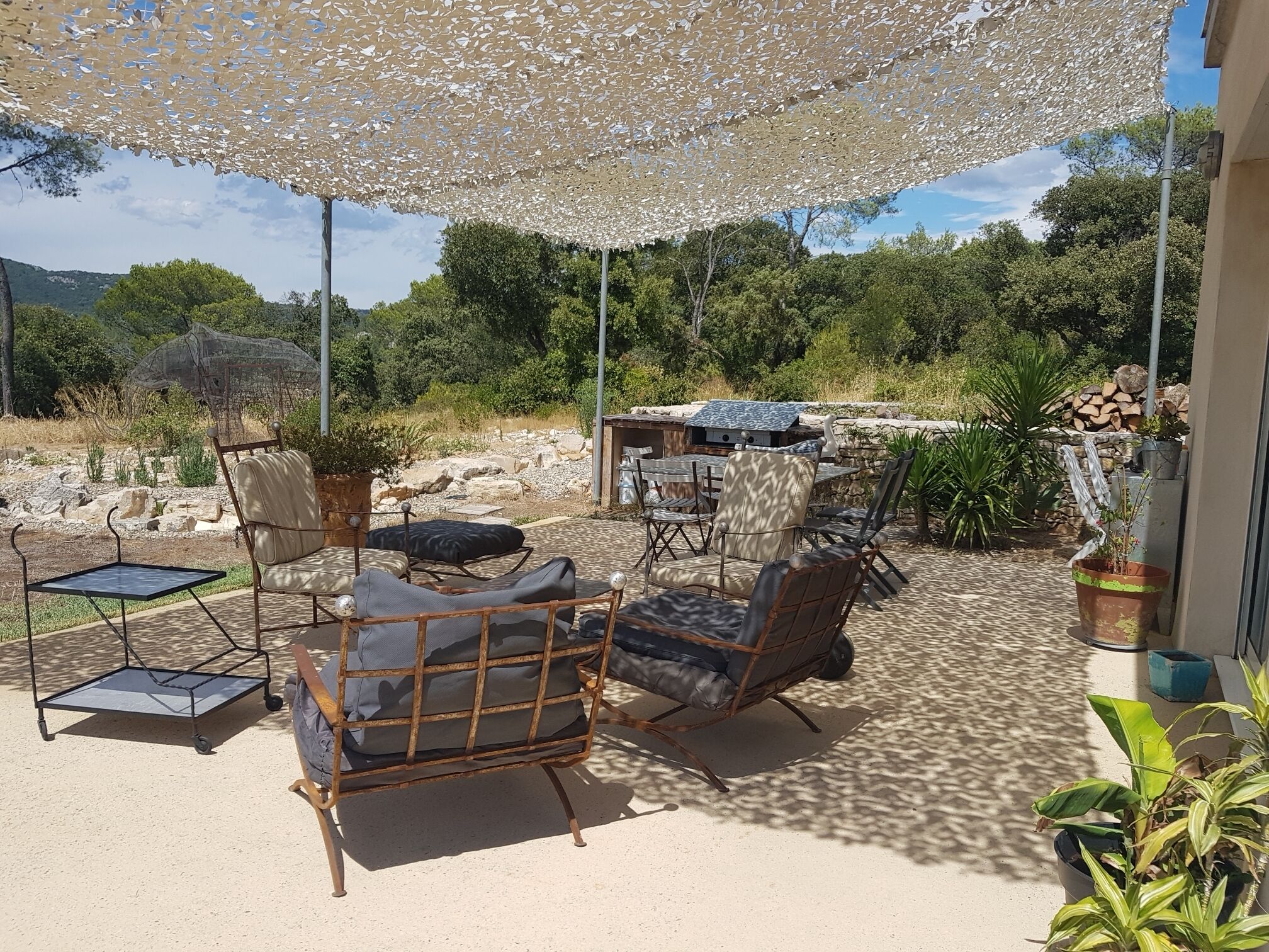 Een terras buiten met een tafel, stoelen, een pergola en uitzicht op het omliggende landschap.