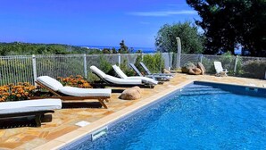 A swimming pool with lounge chairs and a view of the sea. - Beautiful 5* villa with exceptional sea view and secure swimming pool (Porto-vecchio)