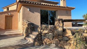 A stucco building with a tiled roof, a stone wall entrance, and a clear sky. - Beautiful 5* villa with exceptional sea view and secure swimming pool (Porto-vecchio)