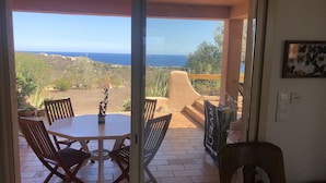 A patio with a table and chairs, a view of the sea, and a balcony with a railing. - Beautiful 5* villa with exceptional sea view and secure swimming pool (Porto-vecchio)