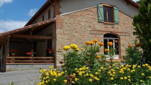 A stone building with a sloped roof and a wooden balcony. - Pool, family rooms, breakfast (Seysses-Savès)