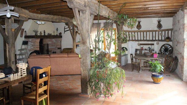 A rustic interior with exposed wooden beams, a brick fireplace, and a dining area with wooden furniture. - Pool, family rooms, breakfast (Seysses-Savès)