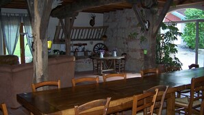A rustic dining area with a wooden table and chairs, a stone wall, and a view of the outdoors. - Pool, family rooms, breakfast (Seysses-Savès)