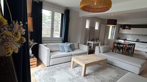 Uma sala de estar moderna com um conjunto de sofás, uma mesa de centro e um espaço de jantar com cadeiras.