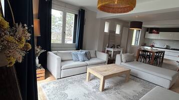 Un salon moderne comprenant un ensemble de canapés, une table basse et un coin repas avec des chaises.