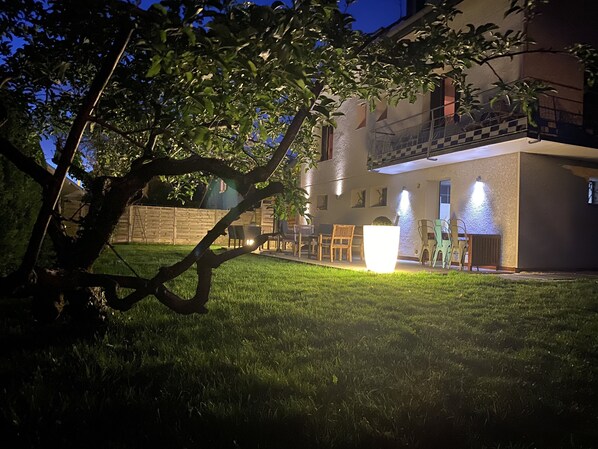 A house with a balcony, outdoor seating, and a well-maintained lawn.