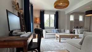 Uma sala de estar moderna com uma escrivaninha de madeira, um sofá cinza e uma área de jantar.
