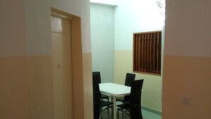 En smal hall leder in till en matplats med ett vitt bord och svarta stolar.