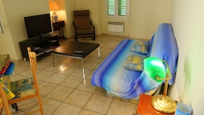 A living room with a sofa, a television, a chair, and a lamp. - Old Nice 41 m2 100 meters sea promenade / Saleya (Nice)