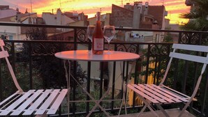 A balcony with a round table, two white chairs, a bottle of wine, and a glass on the table. - 110m2 of relaxation in the center, VISA, sun, sea and mountains (Perpignan)