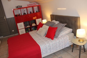 A bedroom with a bed, red and white bedding, a red storage unit, and a bedside table with a lamp. - SMALL JEWEL ALL COMFORT ON THE WINE ROUTE (Jonquières)