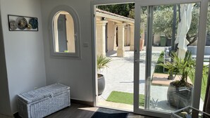 Ein Zimmer mit einer Schiebetür zu einem Außenbereich mit Terrasse, einem Korbsessel und einer Topfpflanze.
