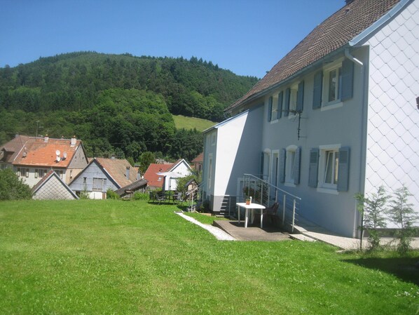 A residential area with houses, a grassy lawn, and a hill in the background.