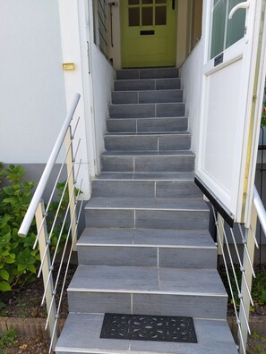 A staircase leading to a door with a metal handrail on both sides.