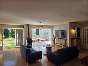 A spacious living room with a large TV, two sofas, and a fireplace.