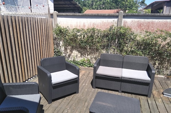 Un patio con mobiliario de mimbre, incluyendo dos sofás y una mesita.