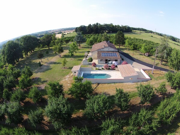 A house with a swimming pool, surrounded by trees and a hilly landscape. - Gîte de groupe, 37 places, 13 rooms (La Romieu)