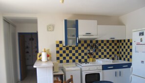 A compact kitchen with a stove, sink, and a small oven. There is a dining table with a patterned tablecloth.