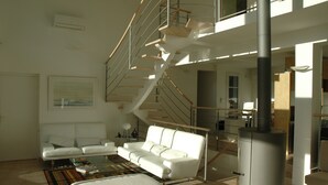 A modern living room with a white sofa, a coffee table, and a staircase leading to an upper level.