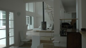 A spacious living area with a staircase, a fireplace, and a kitchen area.