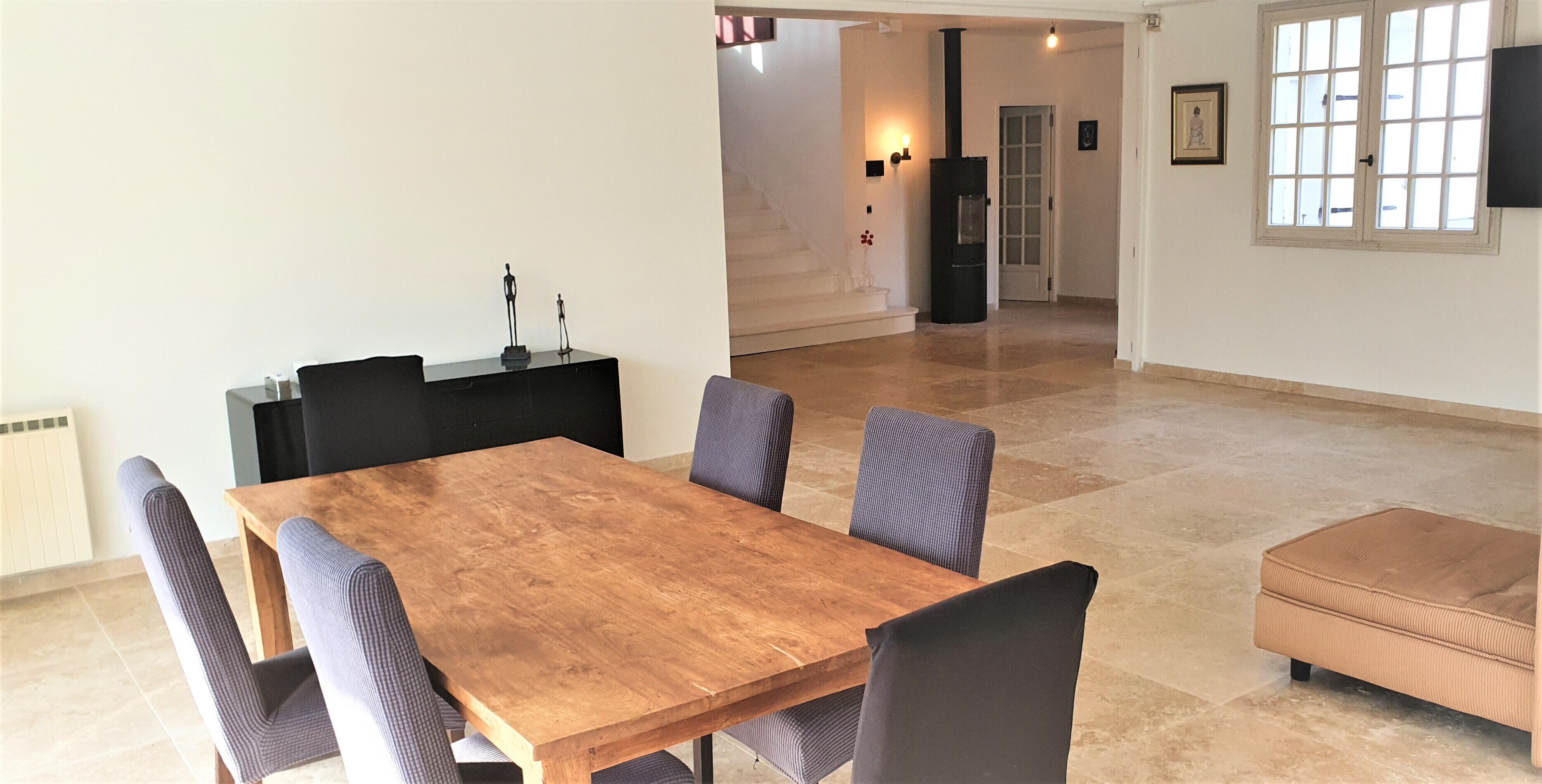 A dining area with a wooden table and six chairs, a black cabinet, and a beige sofa.
