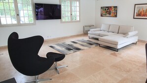 A modern living room with a white sofa, black chair, and dining table. - House 2 minutes walk from the sea (La Ciotat)