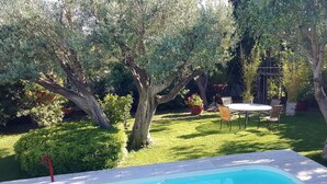 A backyard with a swimming pool, a dining table, and chairs, surrounded by trees and a well-maintained lawn. - House 2 minutes walk from the sea (La Ciotat)
