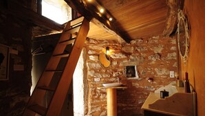A rustic bathroom with a wooden ladder, a stone wall, a sink, and a bathtub.