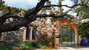 Un bâtiment avec un mur en pierre, une façade rose et une porte verte.