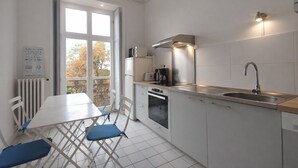 A modern kitchen with white cabinets, a stainless steel sink, and a built-in oven. There is a window with a view of trees outside. - L'intemporel, charming gîte in the Château de St Gervais, 4 to 5 people, 125m². (Saint-Gervais-La-Forêt)