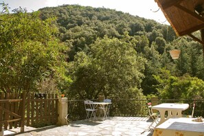 An outdoor patio with a stone floor, a wooden fence, and a table with chairs.