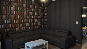 Ein modernes Wohnzimmer mit einem dunkelgrauen Ecksofa, einem weißen Couchtisch und einem großen Bücherregal voller Bücher.