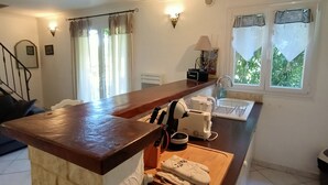 Eine Küche mit Holzausziehtisch, Einbauherd und einem Fenster mit Vorhängen.