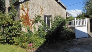 Un bâtiment rustique avec un toit en pente, une porte en bois et un portail blanc.