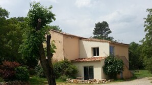 Une maison de plain-pied avec un toit en tuiles, un petit porche et un mur en pierre.