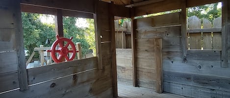 Uma cabana de madeira com telhado inclinado, um volante vermelho à esquerda e um deck de madeira.