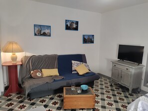 Een woonkamer met een bank, een televisie, een lamp en een salontafel.