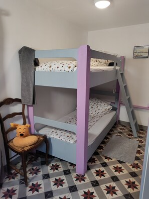 Een stapelbed met een ladder, een stoel met een knuffel en een kamer met een patroon op de vloer.