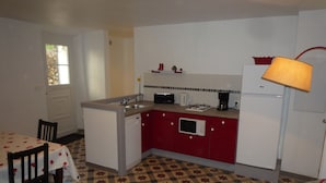 Une cuisine compacte équipée d’un évier, d’une cuisinière, d’un four à micro-ondes et d’un réfrigérateur. On y trouve une table à manger avec des chaises et un sol à motifs.