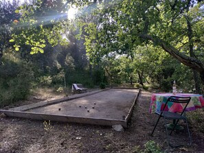 An outdoor billiards table with a wooden frame and a surrounding gravel area.