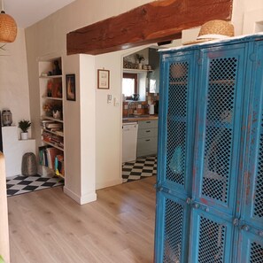 Cozinha com piso xadrez, armário azul e uma viga de madeira acima.