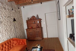Uma sala de estar acolhedora com um armário de madeira, um sofá vermelho e uma mesa de centro com revistas.