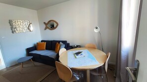 A modern living room with a round table, a sofa, and a coffee table. There is a decorative mirror on the wall and a floor lamp. - Résidence Les Muguets - Apartment 1st floor (Villers-sur-Mer)