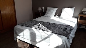 A bedroom with a bed, a nightstand, a lamp, and framed pictures on the wall. - seasonal rental of a villa in the countryside (Meynes)